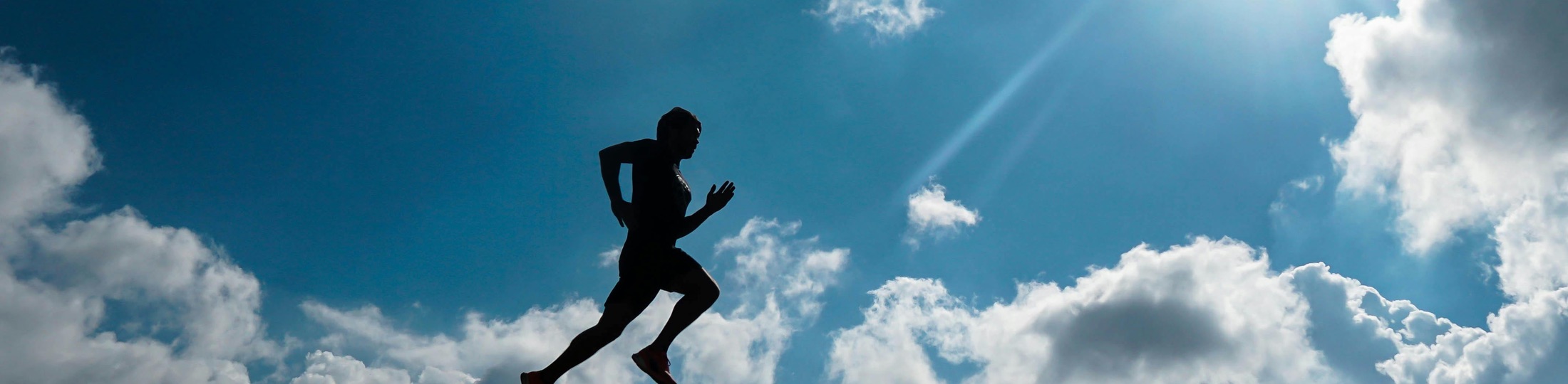 Runner silhouetted against a bright sky